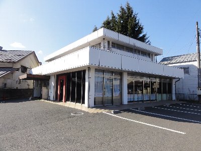 青い空の下に建つ白い外装の仮事務所の建物の写真