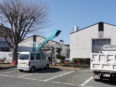 あんずホールの駐車場に車やトラックや重機が駐車されている写真