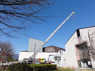 あんずホールの建物の外でクレーン車がクレーンを上側に長く伸ばしている写真