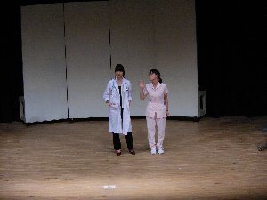 女医の姿をした女性と看護師の姿をした女性が正面を向き話している発表会の写真