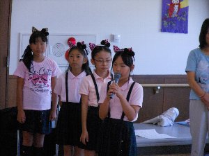 あんず少年少女合唱団の女の子4人のうち一人がマイクを持ち話している写真
