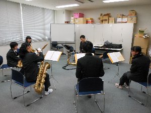 中学校の吹奏楽部が講師を囲ってセミナーを受けている写真