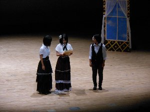 中野西高校演劇部のロングスカートをはいた部員2名と黒いズボンをはいた部員1名が舞台を演じている写真