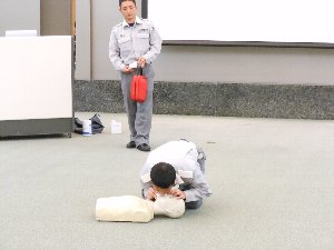 人形を用いて蘇生法の実演を行う男性の写真