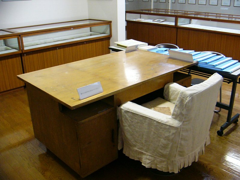 使いこまれた机と白い布張りの椅子の写真