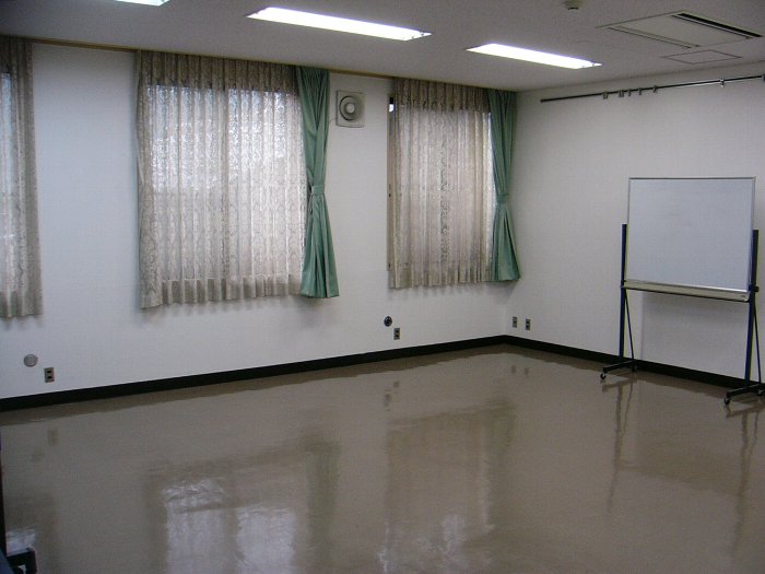 ホワイトボードとカーテンのかかった窓がある小会議室の一角の写真